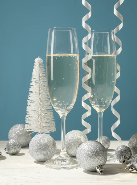 Champagne glasses and baubles against blue background, space for