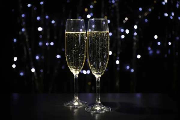 Copas de champán sobre fondo oscuro con luces borrosas, c — Foto de Stock
