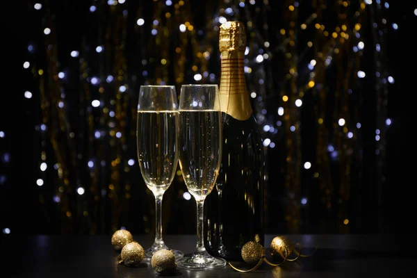 Julgranskulor, champagneglas och flaska på suddig baksida — Stockfoto