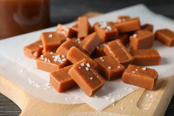 Salted caramel candies on wooden board, close up and copy space — Stock Photo, Image