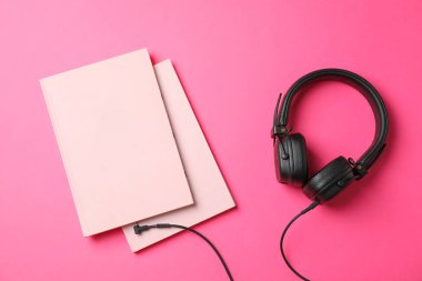 Pembe arkaplan üzerine kitaplar ve kulaklıklar, metin için boşluk