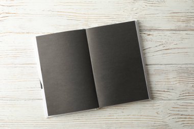 Ahşap zemin üzerinde siyah sayfaları olan boş bir kitap, boşluk 