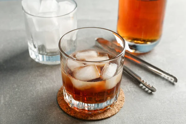Botella, vasos con hielo y whisky sobre fondo gris, c — Foto de Stock