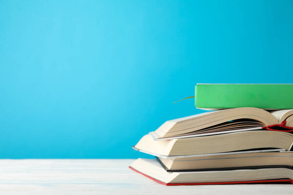 Stack of books against blue background, space for text