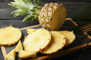 Tahta kesme tahtası ananas ve ahşap arka planda palmiye yaprağı,