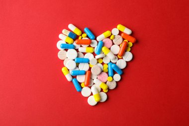 Kırmızı arka planda haplardan yapılmış kalp, mesaj için boşluk. Üst görünüm