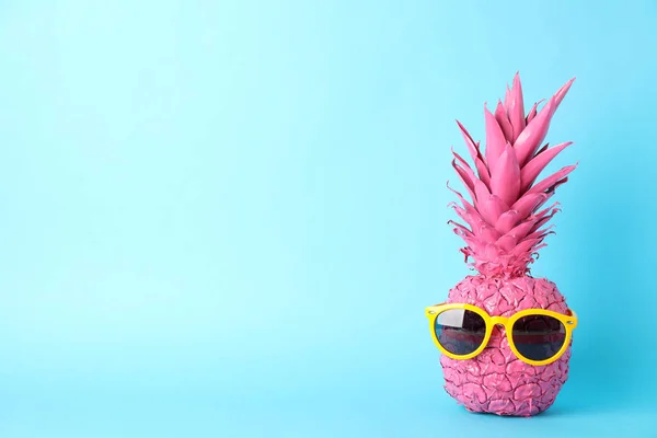 Geschilderde roze ananas met zonnebril op blauwe achtergrond, ruimte — Stockfoto