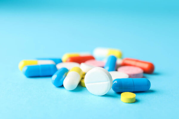 Many pills on blue background, closeup and space for text