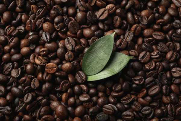 Teksturowane tło ziarna kawy z liściem, zbliżenie — Zdjęcie stockowe