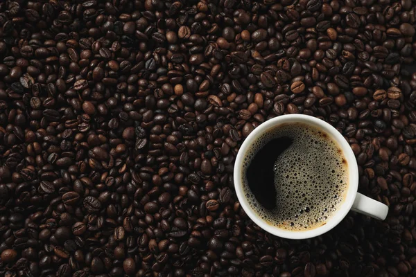 Cup kaffe på kaffebönor bakgrund, ovanifrån — Stockfoto