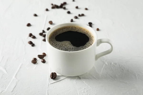 Cup of coffee and beans on white background, close up — Stock Photo, Image