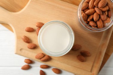 Bir bardak badem sütü, badem tohumları yine beyaz masada.