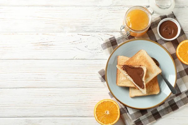 Assiette avec des toasts, orange, confiture, choco crème et serviette sur bois ba — Photo