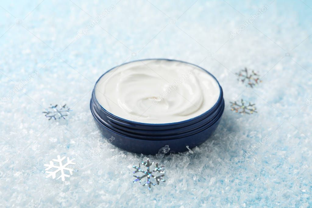 Winter cream for skin on snowy blue background, space for text. 