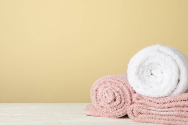 Beyaz ahşap masa üzerindeki katlanmış havlular, bej arka plan, sp
