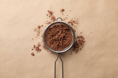 Karton zemin üzerinde kakao tozu olan süzgeç, üst görünüm