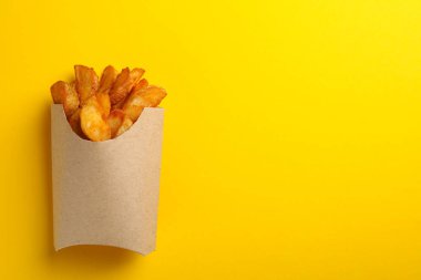 Sarı arkaplanda fırında patates dilimleri, metin için boşluk.