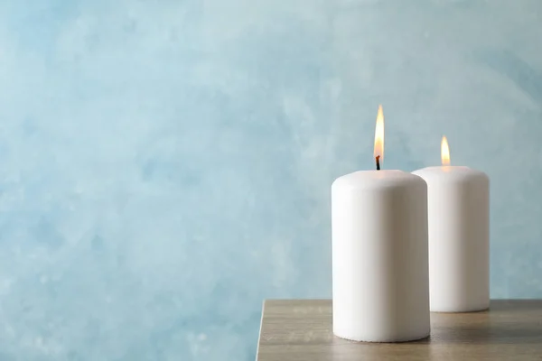 Dos velas encendidas sobre mesa gris sobre fondo azul, espacio — Foto de Stock