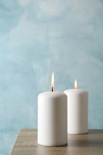 蓝色背景下灰色桌子上的两支燃烧的蜡烛，空间 — 图库照片