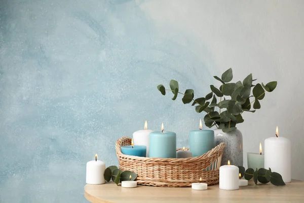 Горящие свечи, корзина и ваза с эвкалиптом против голубой ба — стоковое фото