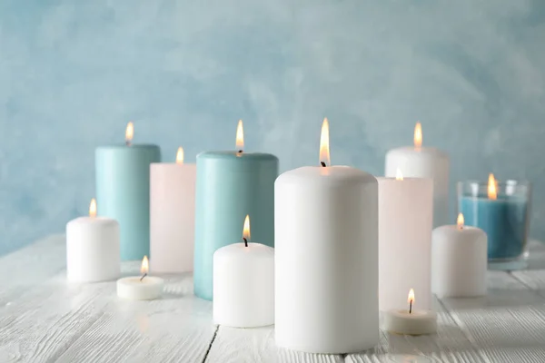 Different burning candles against blue background, space for tex — Stock Photo, Image
