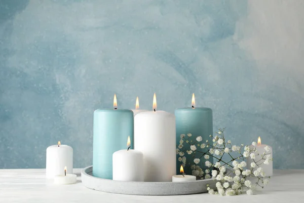在蓝色背景下燃烧蜡烛、盘子和花朵，空间 — 图库照片