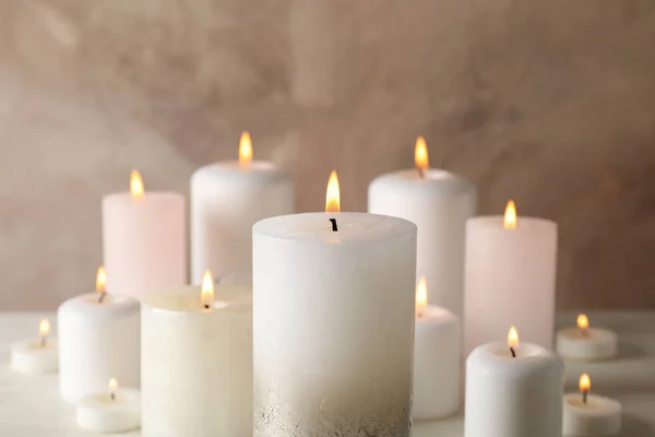 Burning candles against brown background, close up — Stock Photo, Image