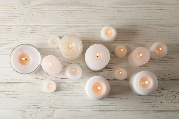 Diferentes velas em chamas no fundo de madeira, vista superior — Fotografia de Stock