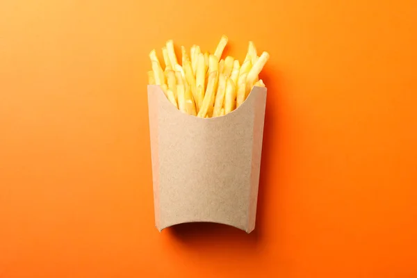 Fatias de batatas fritas quentes na caixa no fundo laranja, espaço fo — Fotografia de Stock