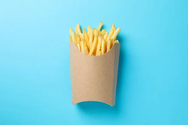 Fatias de batatas fritas quentes na caixa no fundo azul, espaço para — Fotografia de Stock