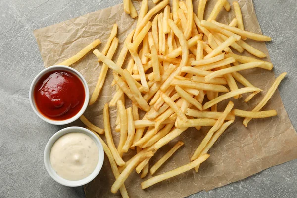 Sabrosas papas fritas, salsas sobre fondo gris, espacio para el texto. T — Foto de Stock