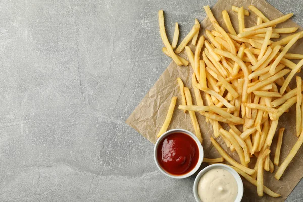 Tasty french fries, sauces on gray background, space for text. T — Stock Photo, Image