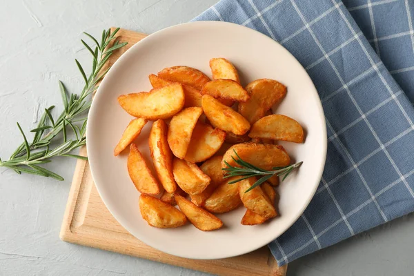 Placa con rodajas de cuñas de patata al horno, servilleta sobre fondo gris —  Fotos de Stock