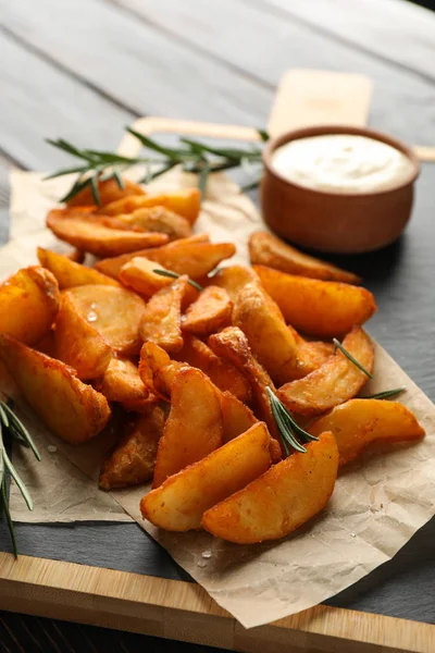 Slices of baked potato wedges, rosemary, white sauce, kitchen bo — Stock Photo, Image