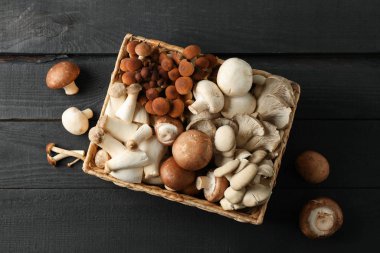 Ahşap arka planda, sepetin içinde farklı mantarlar.