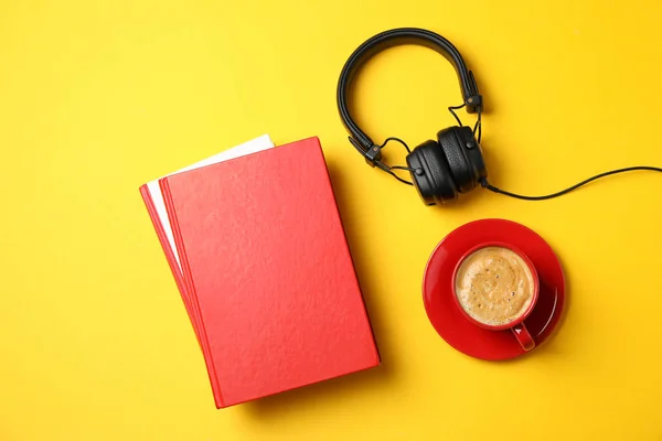Kırmızı kitaplar, kulaklıklar ve sarı arka planda bir fincan kahve. — Stok fotoğraf