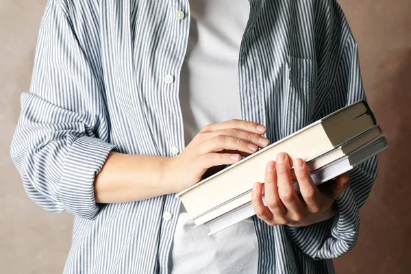 Mulher segurando livros contra fundo marrom, close-up — Fotografia de Stock
