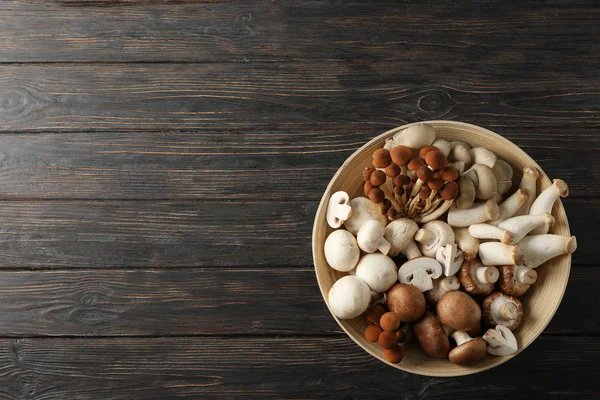 Olika svampar i skål på trä bakgrund, ovanifrån — Stockfoto