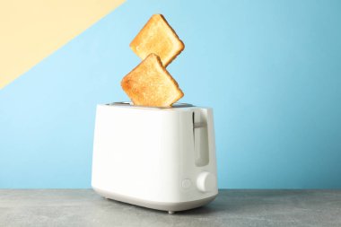 Renk arkaplanı ve alana karşı gri masadaki tost makinesi ve ekmek 