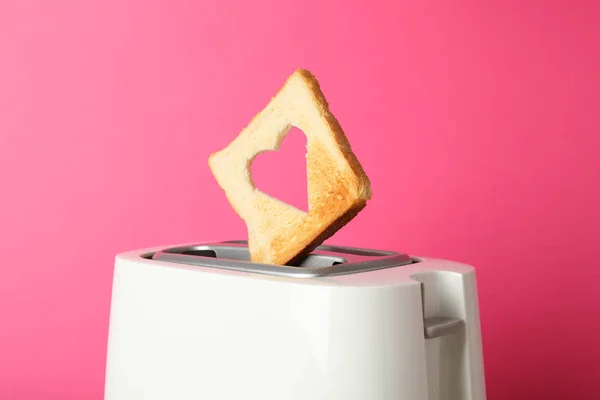 Toaster und Brotscheibe in Herzform auf rosa Hintergrund — Stockfoto