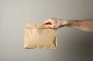 Gri arkaplan üzerinde kağıt paketi olan erkek el için boşluk 