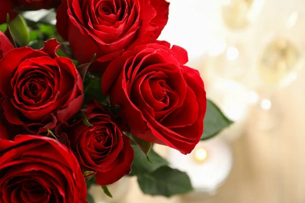 Rote Rosen, aus nächster Nähe. verschwommener Hintergrund mit Kerzen und Gläsern — Stockfoto