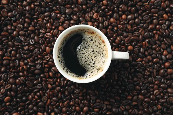 Tazza di caffè su sfondo chicchi di caffè, vista dall'alto — Foto Stock