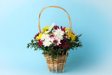 Mavi arkaplanda çiçekli hasır sepet, metin için boşluk