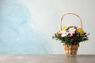 Mavi arka planda gri masadaki çiçekli hasır sepet