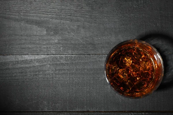 Szklanka whisky z kostkami lodu na ciemnym drewnianym tle, top v — Zdjęcie stockowe