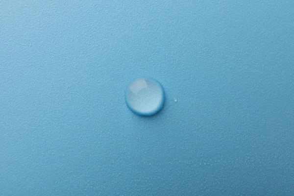 Gota de agua sobre fondo azul, macro y espacio para texto — Foto de Stock