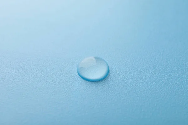 Капля воды на синем фоне, макрос и пространство для текста — стоковое фото
