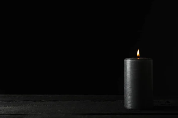 Свеча на деревянном столе на черном фоне, место для текста — стоковое фото