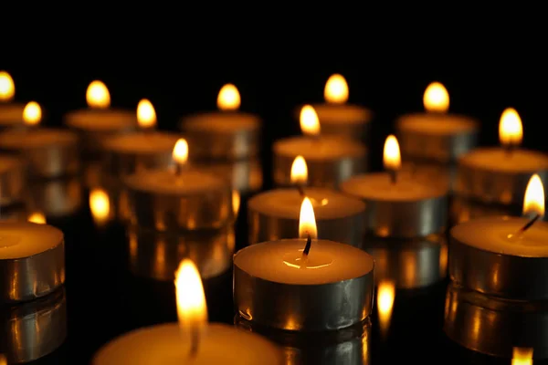 Gruppe brennender Kerzen auf schwarzem Hintergrund, Nahaufnahme — Stockfoto
